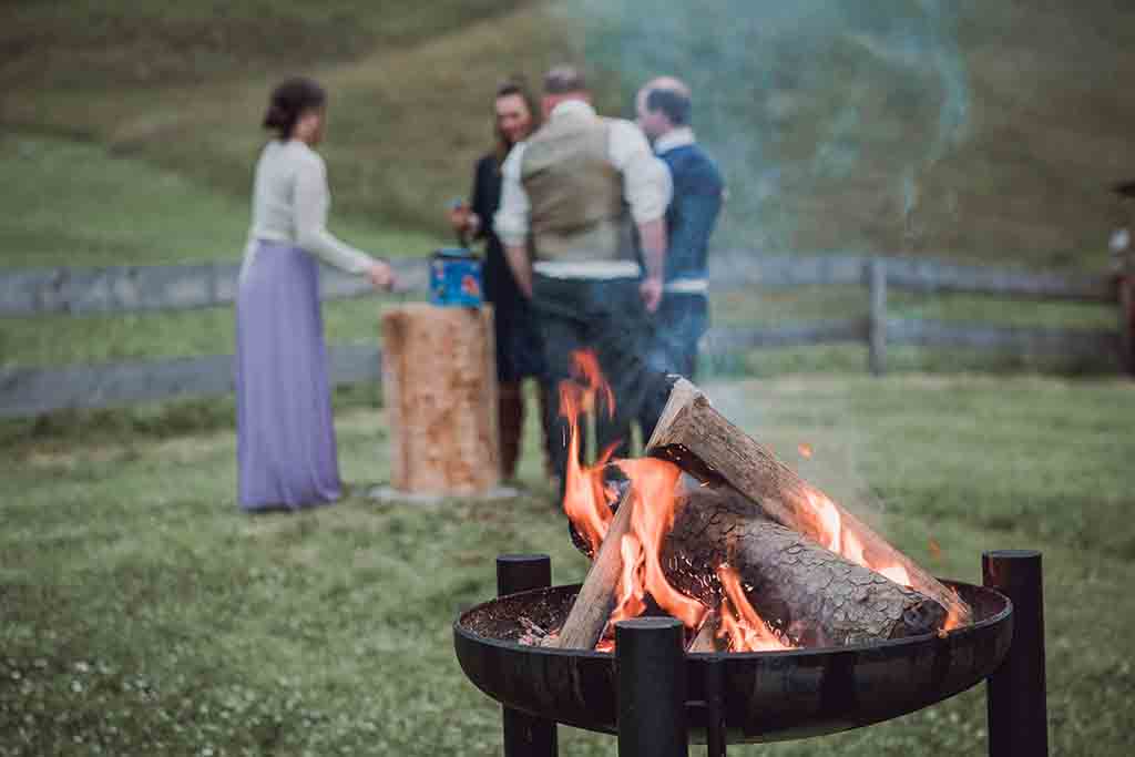 Ein loderndes Lagerfeuer mit Gästen im Hintergrund im stettli resort in Churwalden