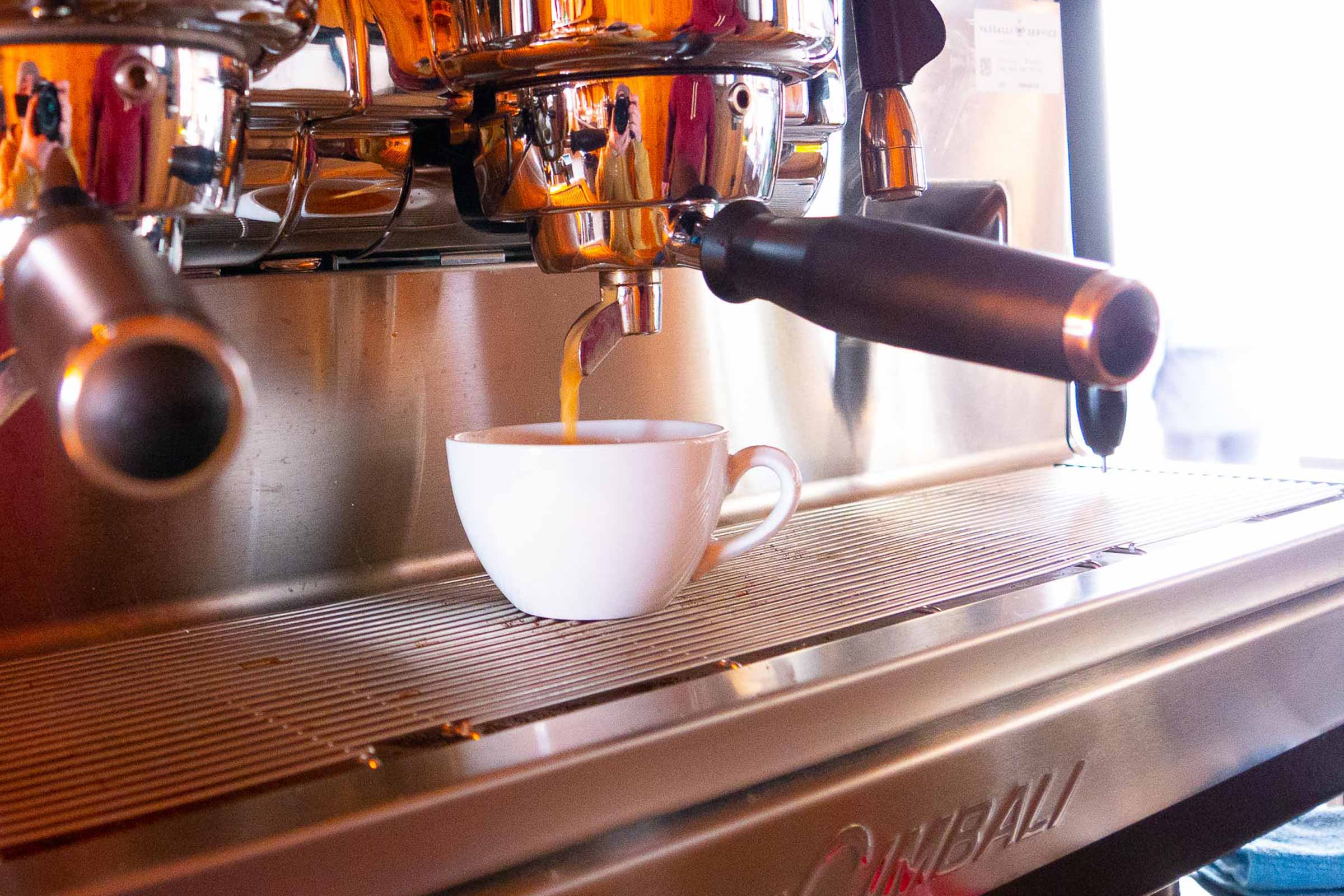 Frischer Kaffee läuft aus der Espressomaschine ins weisse Porzellan